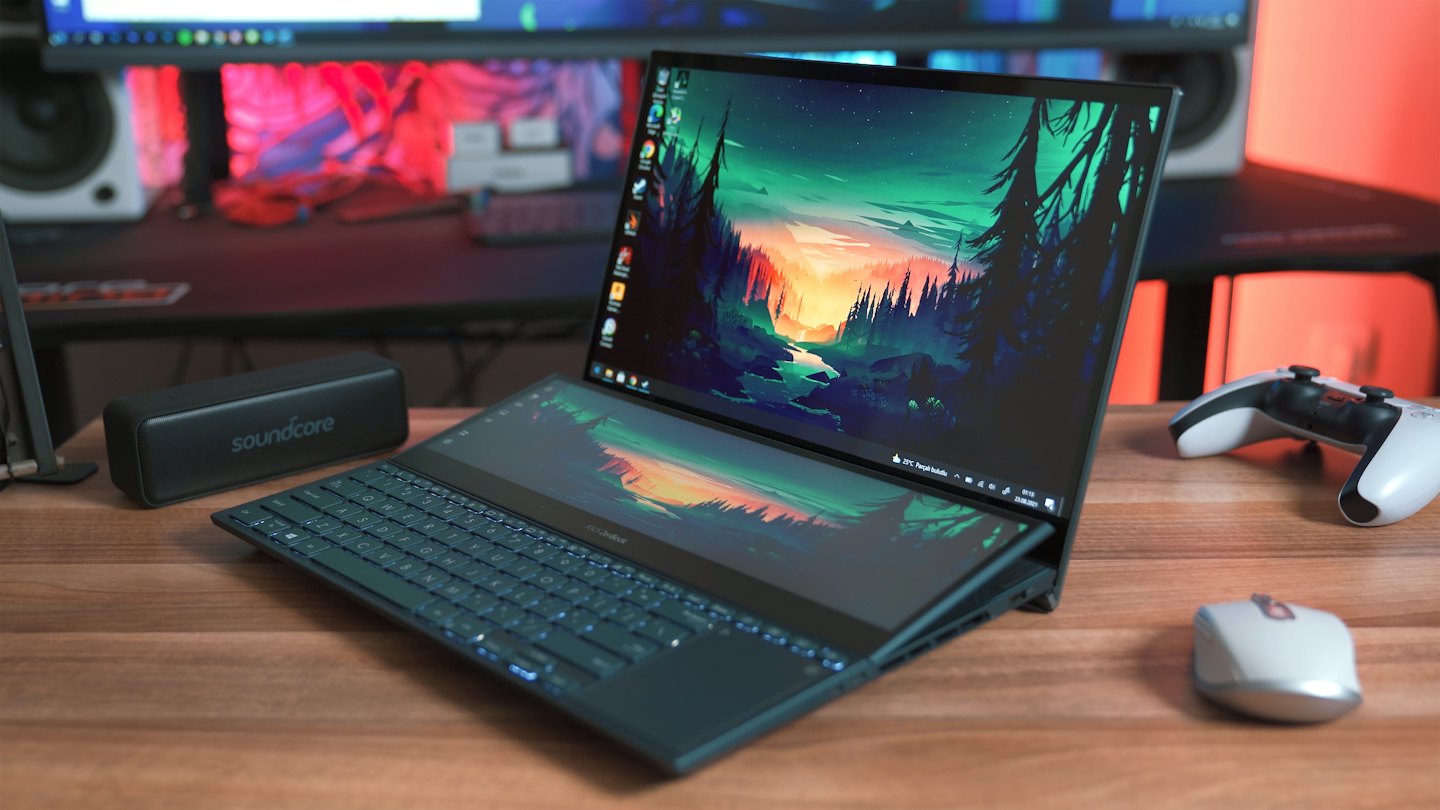 Laptop met twee schermen toont landschapsachtergrond op een houten bureau.